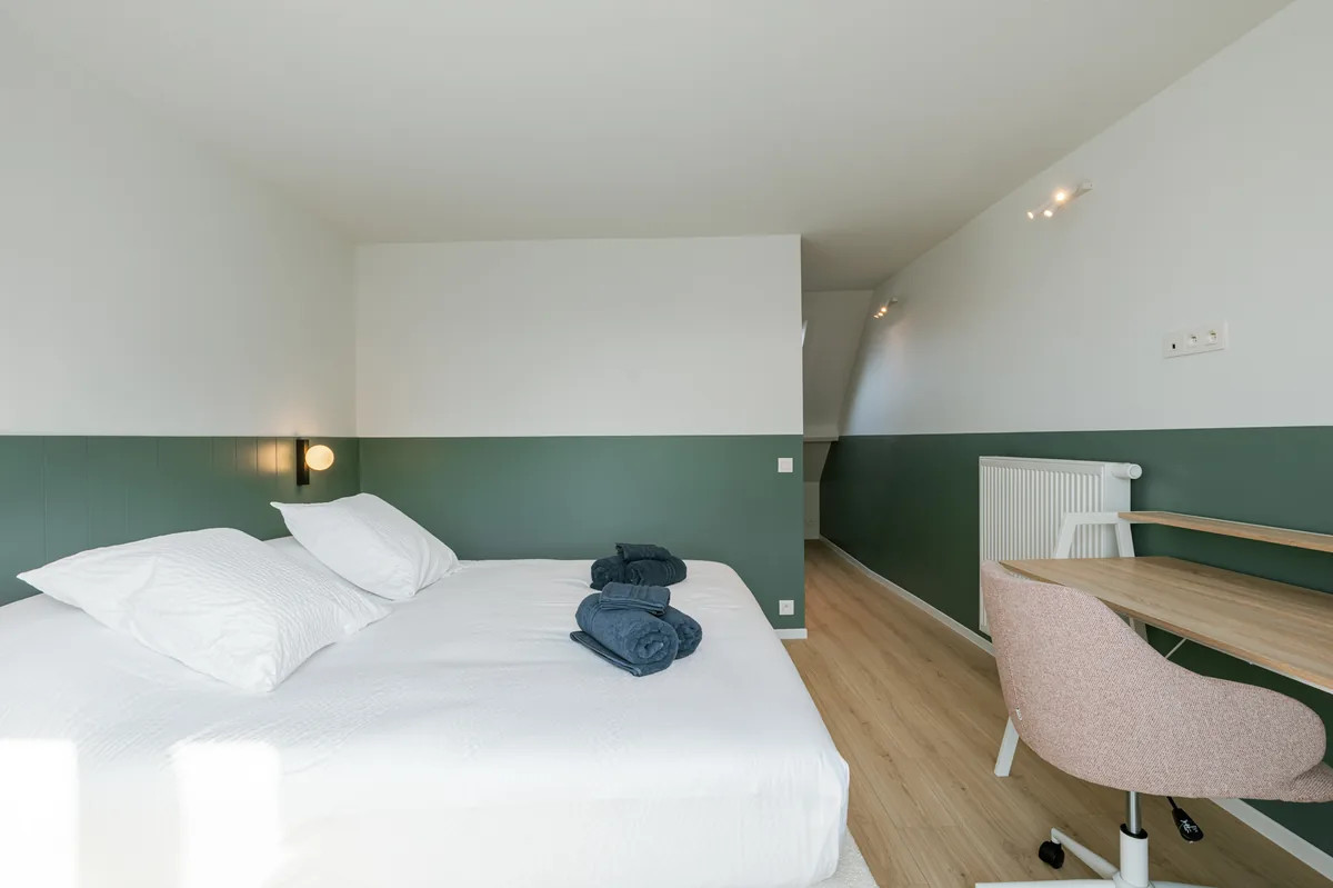 Slaapkamer met dubbel bed en werkplek
